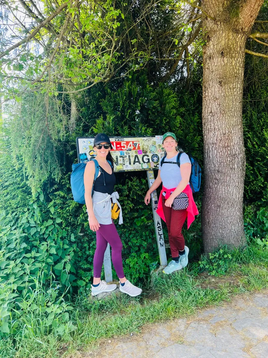 Lauren and Leah beside a road sign marked Santiago