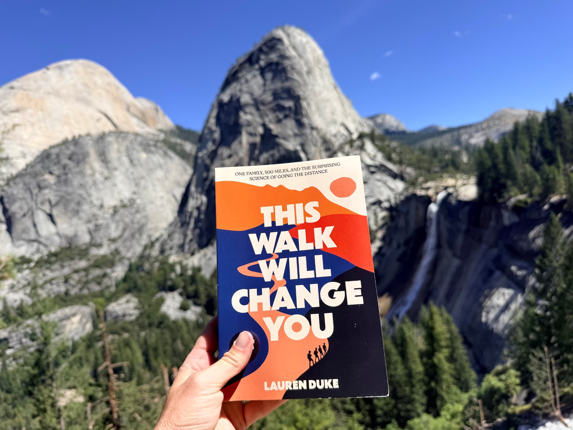 The book held up in front of Nevada Fall in Yosemite